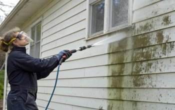 Person using a top-rated pressure washer to clean the siding of a house, revitalizing the exterior