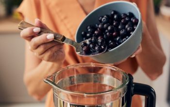 Fresh blueberries being measured in a clear measuring cup showing volume to weight conversion