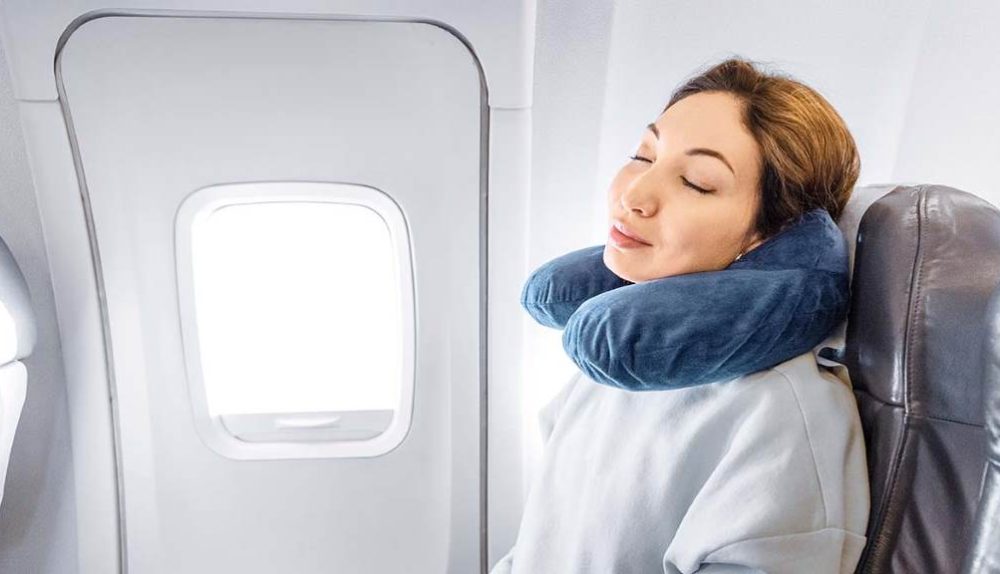 Woman sleeping peacefully on plane with twisted Dot&Dot memory foam travel pillow supporting her neck