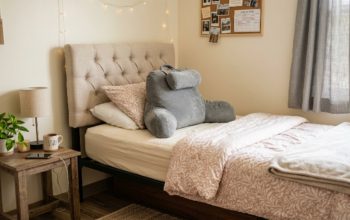A soft tufted headboard attached to a dorm twin XL bed with a back support pillow placed against it