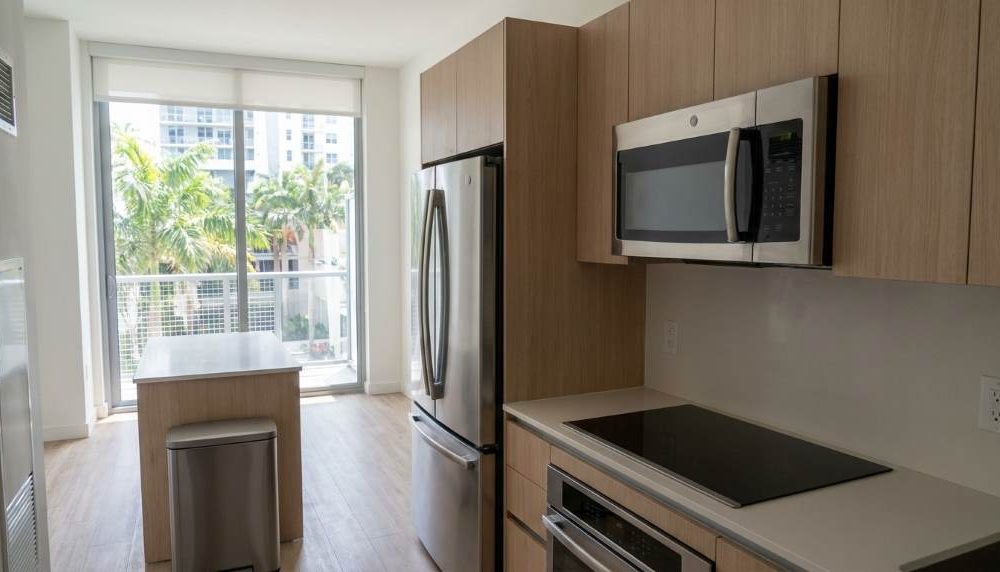 Modern Miami apartment kitchen with aligned stainless steel appliances