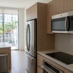 Modern Miami apartment kitchen with aligned stainless steel appliances